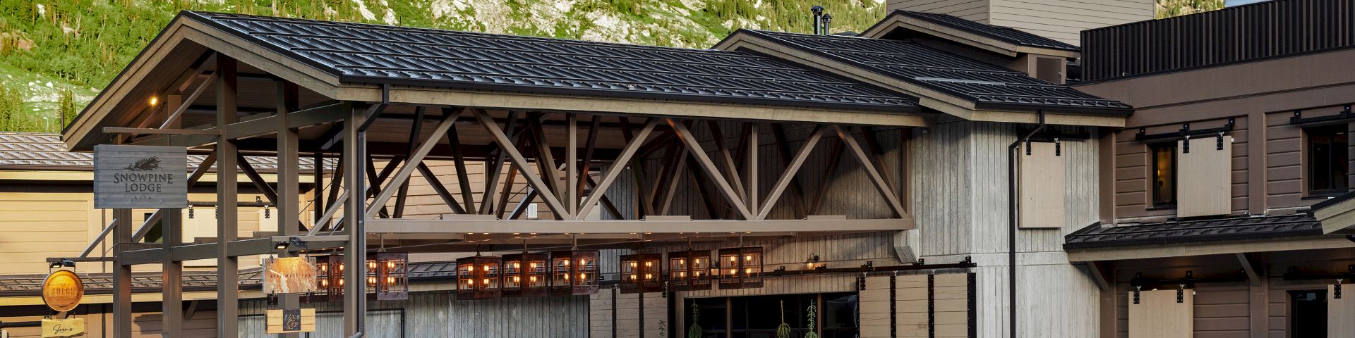 A wooden lodge building with the &ldquo;Snowline Lodge&rdquo; sign, surrounded by a green mountain valley.