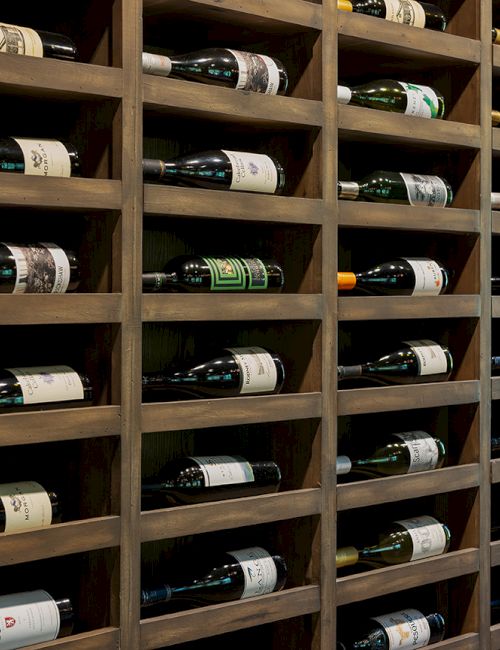 A wooden wine cellar rack filled with neatly stored bottles of wine.