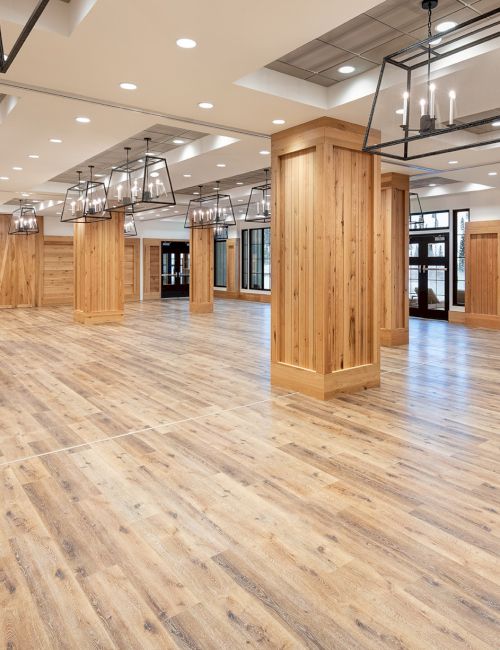 A modern indoor hall with wood-paneled walls, polished flooring, and multiple hanging lantern-style lights.